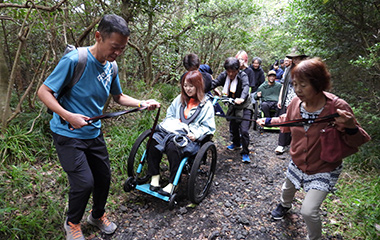 トレッキングコースで車いすをサポートする様子