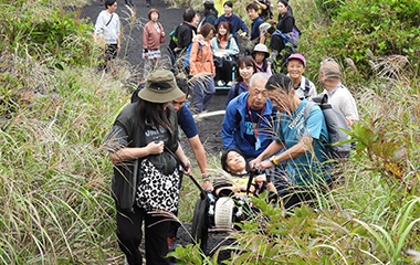 トレッキングコースで車いすをサポートする様子
