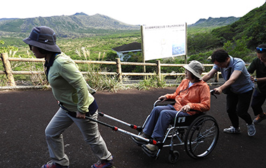 トレッキングコースで車いすをサポートする様子